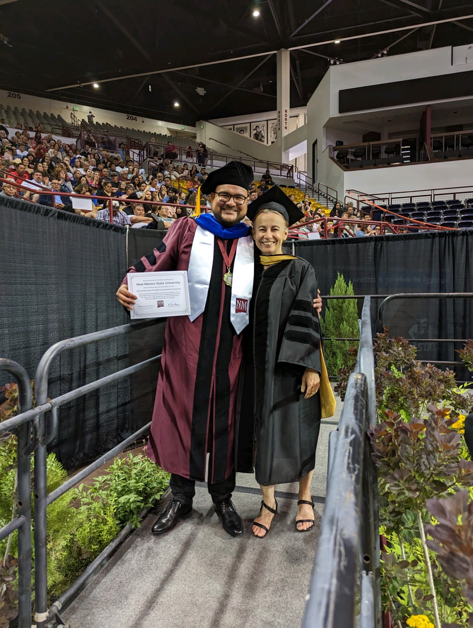 Dr. Eduardo Hernandez in his grad robes standing next to Dr. Kathy Hanley